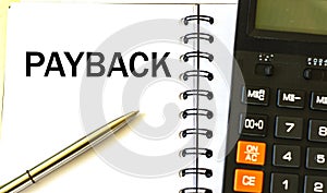 PAYBACK word in a notebook against the background of calculitar photo