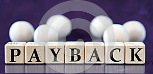 PAYBACK - word on wooden cubes on a blue background with wooden balls