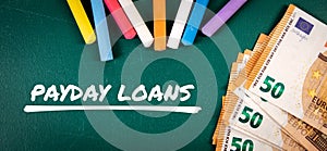 PAYDAY LOANS. Money and colored pieces of chalk on a green board