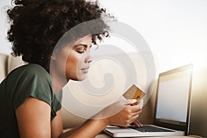 Paying the bills. a woman using her laptop on the sofa at home while holding a bankcard. photo