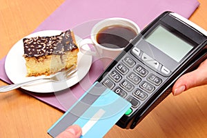 Paying with contactless credit card for cheesecake and coffee in cafe, finance concept