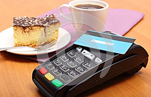 Paying with contactless credit card for cheesecake and coffee in the cafe, finance concept