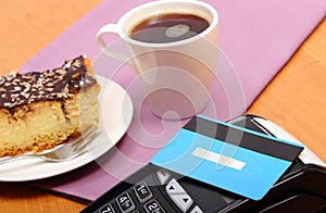 Paying with contactless credit card for cheesecake and coffee in the cafe, finance concept