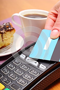 Paying with contactless credit card for cheesecake and coffee in the cafe, finance concept