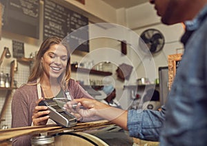 Paying for his purchases conveniently and securely. a store assistant taking a payment from her customer using his