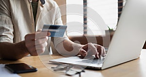 Payment online. Man holding credit card and using laptop at home. Businessman working on computer in office.