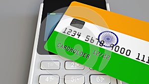 Payment or POS terminal with credit card featuring flag of India. Indian retail commerce or banking system conceptual 3D