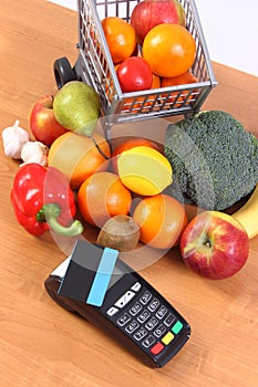 Payment terminal with contactless credit card, fruits and vegetables, cashless paying for shopping