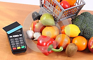 Payment terminal with contactless credit card, fruits and vegetables, cashless paying for shopping