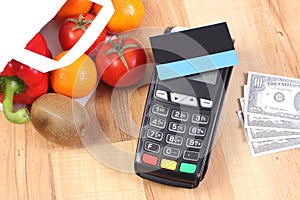 Payment terminal with credit card and dollar, fruits and vegetables, cashless paying for shopping