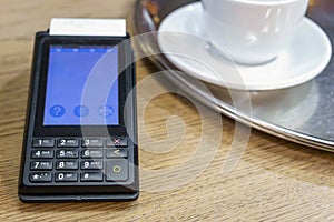 Payment terminal with nfc technology on a tray with a cup in a restaurant. Payment of breakfast with tpv