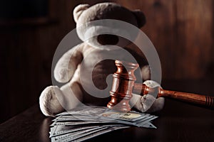 Payments alimony. Wooden judge gavel, dollar banknotes and teddy bear close-up. Divorce and separation concept
