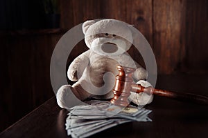 Payments alimony. Wooden judge gavel, dollar banknotes and teddy bear. Divorce and separation concept