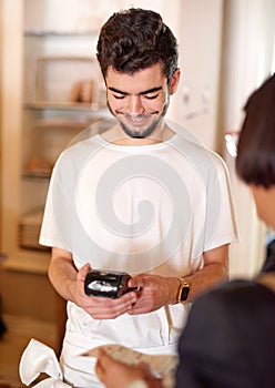 Payments made easy. a young shop assistant helping a customer with a payment terminal in a shop.