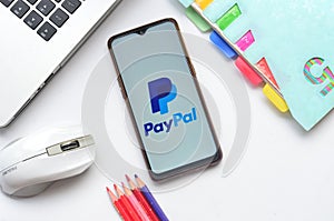 paypal apps on smartphone with laptop and book