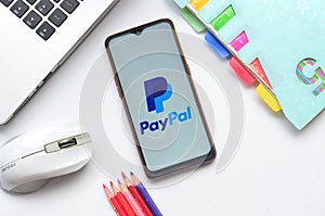 paypal apps on smartphone with laptop and book