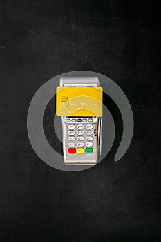 Paypass technology. Bank card lays on payment terminal on black background top view copy space