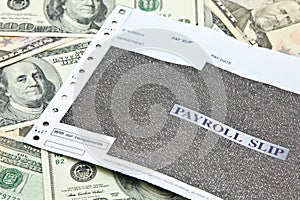 Payroll slip on pile of US dollar banknotes