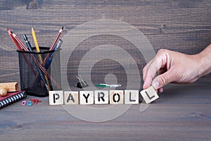 Payroll. Wooden letters on dark background