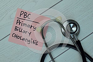 PBC - Primary Biliary Cholangitis write on sticky notes isolated on Wooden Table. Medical concept