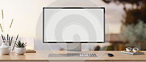 A PC computer mockup and accessories on a wooden desk with a blurred background of an outdoors