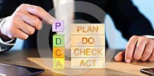 PDCA Cycle Management concept. man stacks wooden blocks with the inscription PDCA.