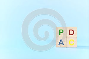 PDCA or Plan Do Check Act cycle method concept. Hand putting action wooden blocks in blue background with copy space.