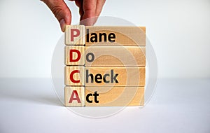 PDCA, plan do check act symbol. Businessman hand. Wooden cubes and blocks with words `PDCA, plan do check act`. Beautiful white