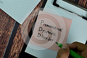 PDD - Premenstrual Dysphoric Disorder write on sticky notes isolated on Wooden Table