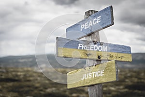 Peace freedom justice text quote on wooden signpost outdoors, written on the ukranian flags