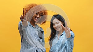 Peace gesture. Two funny young female friends showing peace sign. Multyracial friendship concept