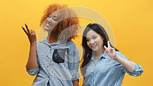 Peace gesture. Two funny young female friends showing peace sign. Multyracial friendship concept