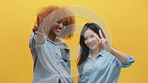 Peace gesture. Two funny young female friends showing peace sign. Multyracial friendship concept
