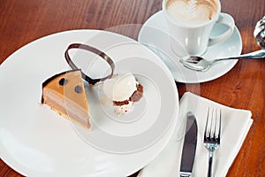Peace of layered souffle dessert with chocolate sauce on plate, on wooden table