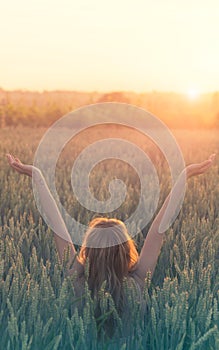 Peace and love, hipster woman celebrates the birth of the sun in a wheat field