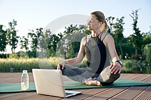 Peace of mind. Athletic beautiful middle aged woman watching instructional videos on a laptop while relaxing on a mat in photo