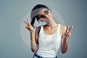 Peace out yall. Studio portrait of a beautiful young woman giving you two peace signs against a grey background.