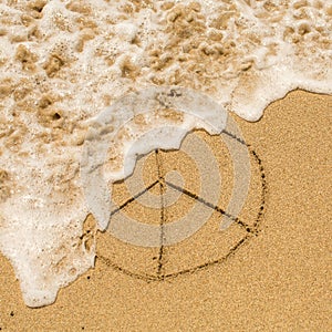 Peace sign drawn on the sand of a beach with the soft wave.