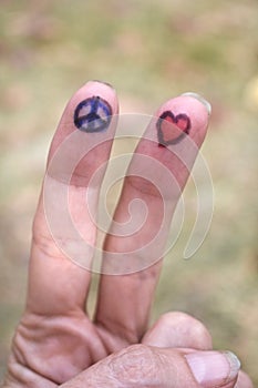 Peace sign and heart shape drawings on fingers close up
