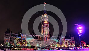 Peace Tower at Centre Block of Canadian Parliament at night with the light show on the facade.