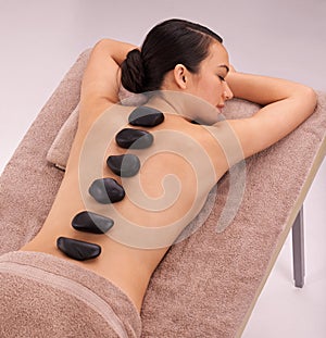 Peace, woman and massage with hot stone therapy and wellness with vacation, relax or rocks. Natural, person or girl with