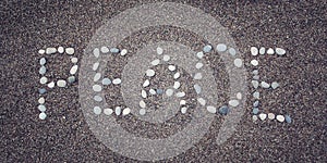 'Peace' word on the sand. Written with pebbles. Aged photo.