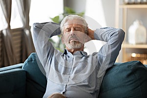 Peaceful 60s old man relax on couch in living room