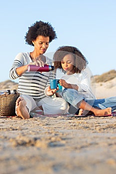 Peaceful African American mother and daughter on picnic on beach