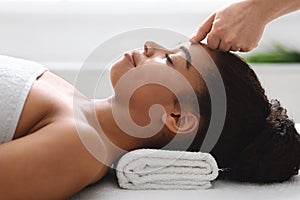 Peaceful african woman getting acupressure massage at modern luxury spa