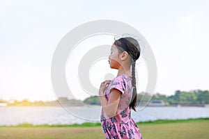 Peaceful Asian little girl closed eyes standing alone in the nature garden