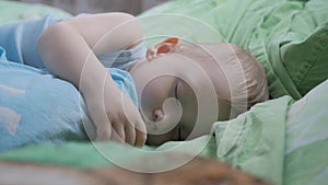 Peaceful baby boy lying on a bed while sleeping. Family, motherhood, love, health and care concept.