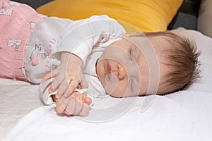 Peaceful baby lying on a bed while sleeping. The baby girl is 2 months old