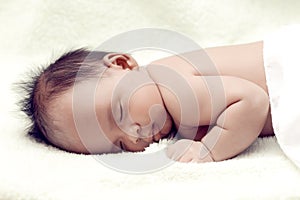 Peaceful baby lying on a bed while sleeping in a bright room