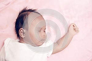 Peaceful baby lying on a bed while sleeping in a bright room